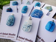 several business cards with blue and white glass cabochons on them sitting on a bench