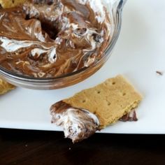 a plate with some crackers and chocolate spread on it next to a bowl of dip