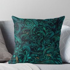 a blue and green throw pillow sitting on top of a couch