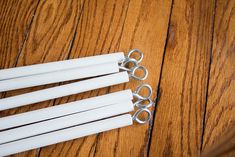 four pairs of scissors sitting on top of a wooden floor next to some white sticks