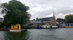 two boats in the water next to buildings and trees on either side of the river