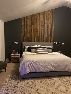 a bedroom with a large bed and wooden headboard on the wall, along with two night stands