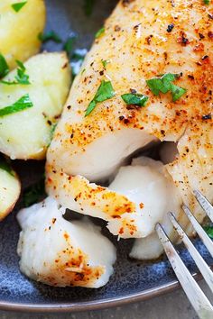 a close up of a plate of food with chicken and potatoes on it, next to a fork