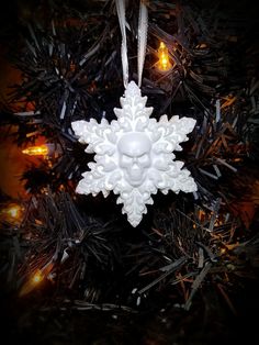 a white snowflake ornament hanging from a christmas tree