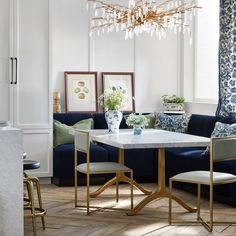 a living room filled with furniture and a chandelier hanging from the ceiling over a table