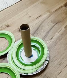 three green plates sitting on top of a wooden floor next to a roll of toilet paper