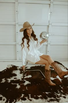 a woman sitting on top of a chair holding a silver ball