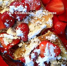 strawberries and other fruit are on top of french toast with powdered sugar in the middle