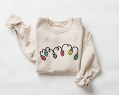 Christmas Lights Sweatshirt, Christmas Sweater, Christmas Crewneck, Womens Christmas Shirt, Tis the Season Sweater, Cute Christmas Tops  This crewneck sweatshirt is pure comfort. Made from a soft cotton/poly blend with no itchy side seams, this is sure to become a staple. SIZE AND FIT: Your sweatshirt design will be printed on a high-quality, soft and comfortable unisex sweatshirt. Sizes run true to size, which takes the guesswork out of ordering; if you like your sweatshirts loose or oversized, Christmas Light Sweater, Festive Cozy Crew Neck Sweater, Trendy Christmas T-shirt Crew Neck, Cozy Christmas Crew Neck Sweater, Outfit Ideas Shirt, Cozy Holiday Crew Neck Sweatshirt, Shirt Outfit Ideas, Shirt Design Ideas, Sweatshirt Ideas