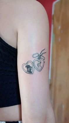 a woman's arm with two heart shaped tattoos on the left side of her arm