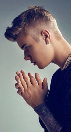 a young man is praying with his hands together