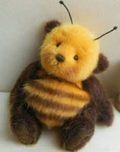 a teddy bear with a bee on it's chest sitting next to another stuffed animal