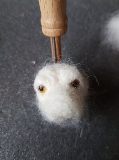 a close up of a small white object on the ground next to a wooden stick