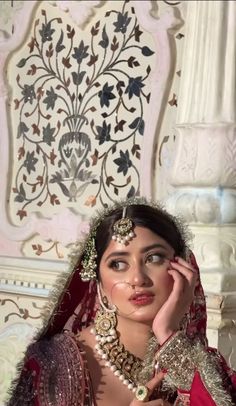 a woman in a red and gold bridal outfit posing for the camera with her hands on her face