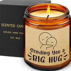 a candle that is sitting in front of a box with the words sending you a big hug on it