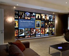 a living room filled with furniture next to a large window covered in movie posters on the wall