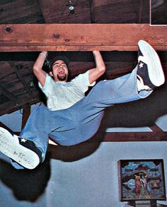 a man is hanging upside down on the ceiling with his feet up and one foot in the air