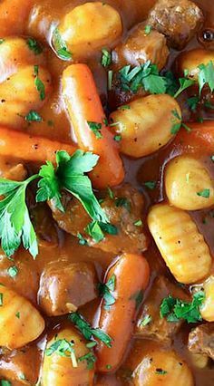 a stew with carrots, potatoes and parsley in a brown gravy