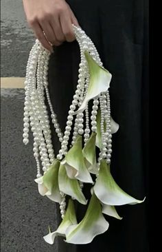 a woman is holding some white flowers and pearls