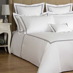 a bed with white sheets and pillows in a room