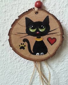 a black cat with green eyes is sitting on a piece of wood and has a red bead in it's ear