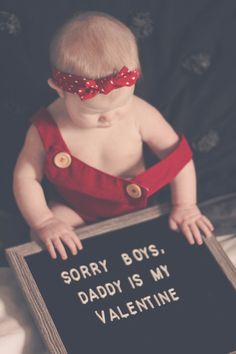 a baby sitting on top of a bed holding a sign that says sorry boys, daddy is my valentine