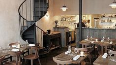 an empty restaurant with tables and chairs in front of a spiral stair case that leads up to the second floor