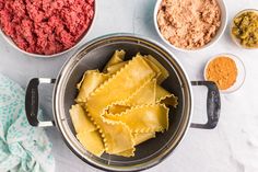 pasta and other ingredients are in bowls on the counter top, including meat sauces