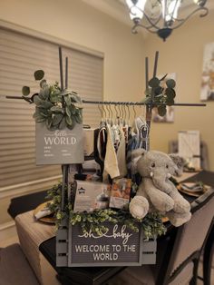 a teddy bear sitting on top of a wooden table next to a sign that says welcome to the world