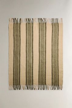 a beige and green striped rug hanging on the wall