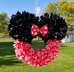 a minnie mouse wreath with red and white polka dots on it in the middle of a grassy area