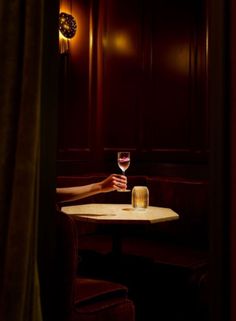 a person sitting at a table with a wine glass in front of them and a clock on the wall