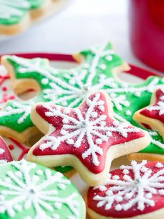 christmas cookies decorated with icing and snowflakes are on a plate next to a red cup