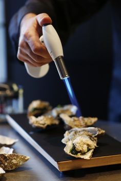 a person is using an electric device to cut oysters on a cutting board,