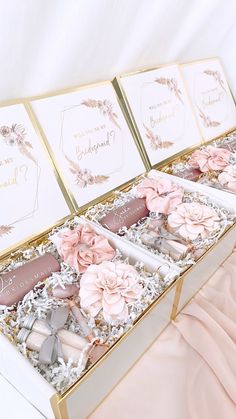 two open boxes filled with pink and white flowers on top of a bed next to each other