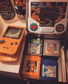 an orange gameboy sitting on top of a table next to other games and accessories