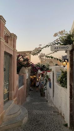 an alley way with flowers growing on the buildings and signs above it that read atetrio