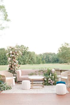 an outdoor seating area with flowers and greenery on the walls, couches and tables