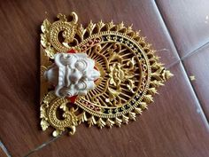 an intricately decorated wall light on a wooden floor with gold accents and red beads