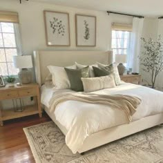 a large white bed sitting in a bedroom next to two windows