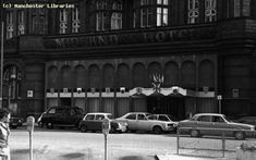 an old black and white photo of cars parked in front of a building on the street