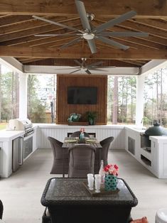 an outdoor living room with furniture and a flat screen tv mounted on the wall above it