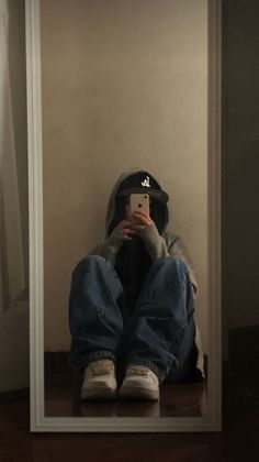 a person sitting in front of a mirror taking a selfie with their cell phone