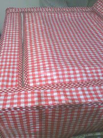 a red and white checkered table cloth on top of a bed with two pillows