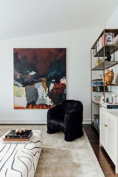 a living room with a large painting on the wall and a black chair in front of it