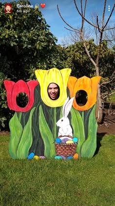 a man is in the grass with some fake flowers and an easter bunny sitting on it