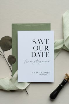 save - our - date card with calligraphy on it next to a pen and flowers