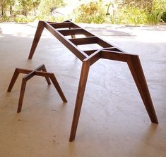 a wooden table sitting on top of a white floor next to a small stool with one leg up