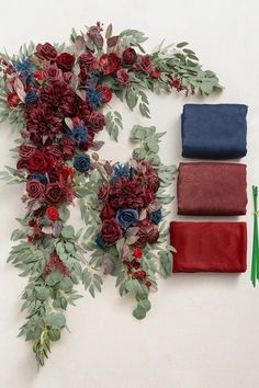 flowers and foliage are arranged on the wall next to folded napkins, one with green leaves