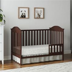 a baby's crib in a white room with two panda pictures on the wall